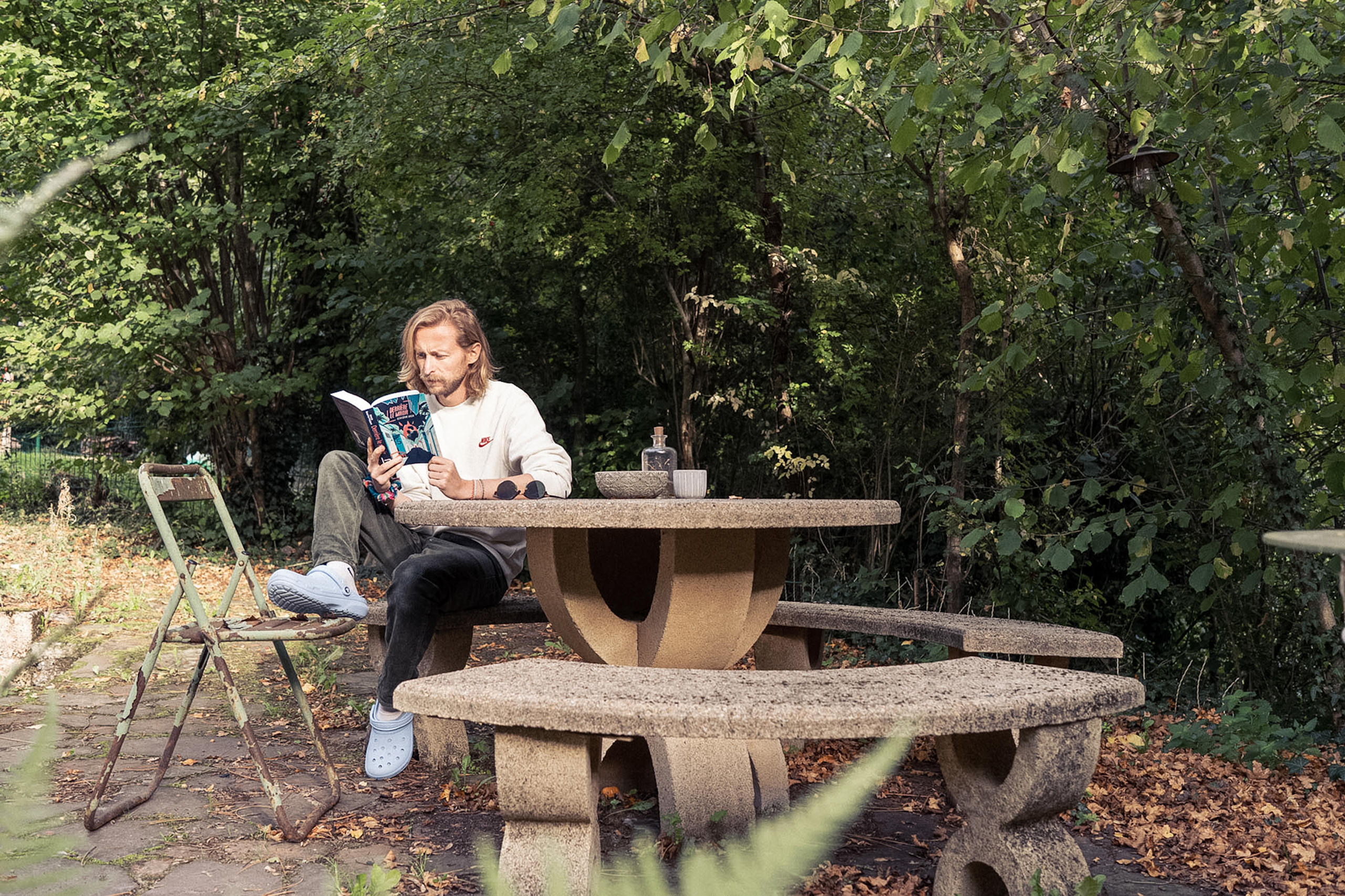 Jason Dejaegere reading Derrière le miroir in a garden